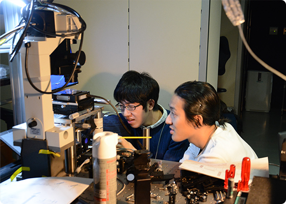 顕微鏡で実験する学生ふたり