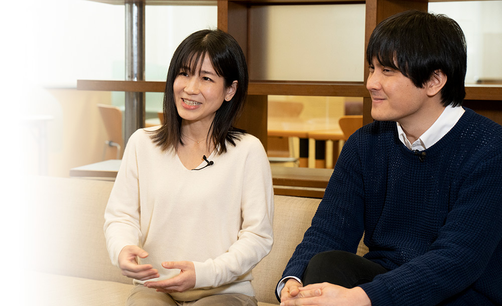 カジュアルな着こなしでソファに座り、インタビューに答える若い研究者夫婦